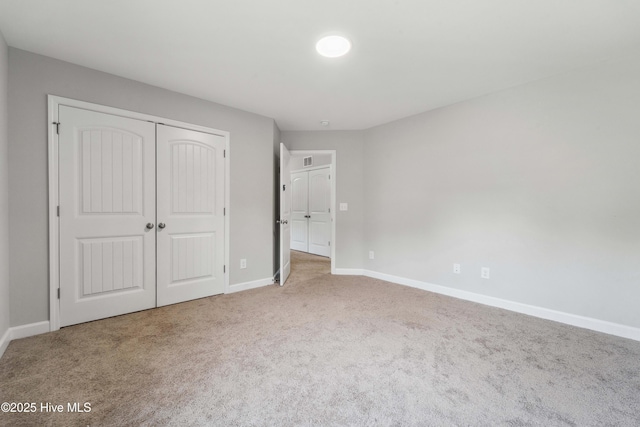 unfurnished bedroom featuring carpet, baseboards, and a closet