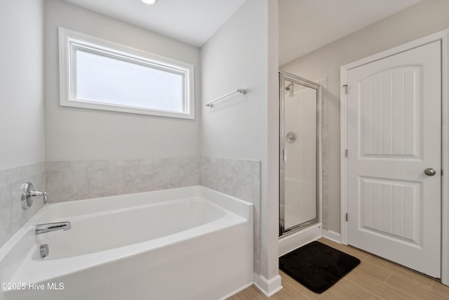 full bath with a stall shower, a bath, and baseboards
