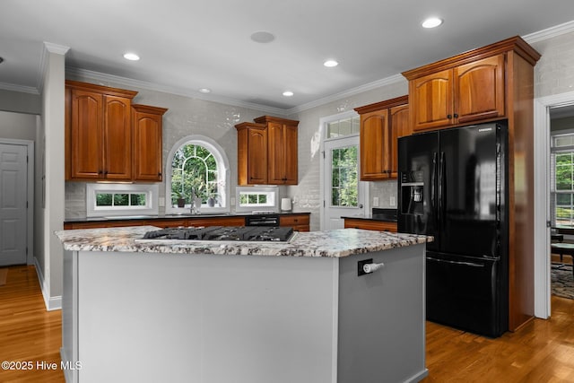102 Silver Creek Landing Rd, Swansboro, NC 28584 - kitchen featuring freestanding refrigerator, stainless steel gas stovetop, a center island, light wood-style flooring, and ornamental molding