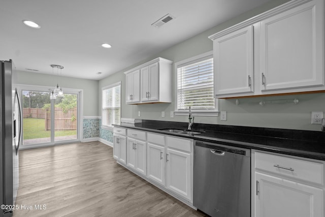 kitchen with stainless steel appliances, a sink, white cabinets, dark countertops, and recessed lighting