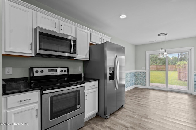 kitchen featuring appliances with stainless steel finishes, dark countertops, white cabinetry, light wood-style flooring, and baseboards