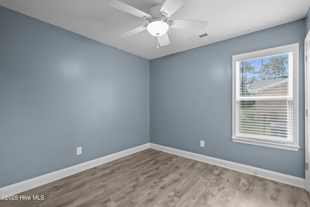 spare room featuring wood finished floors, baseboards, and a ceiling fan