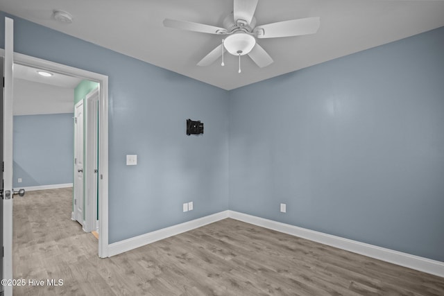 empty room featuring a smoke detector, wood finished floors, and baseboards