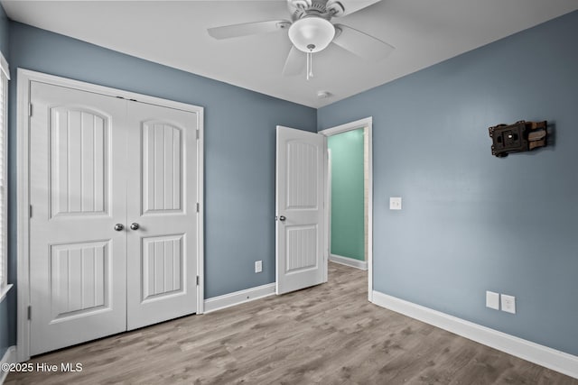 unfurnished bedroom with baseboards, a closet, wood finished floors, and ceiling fan