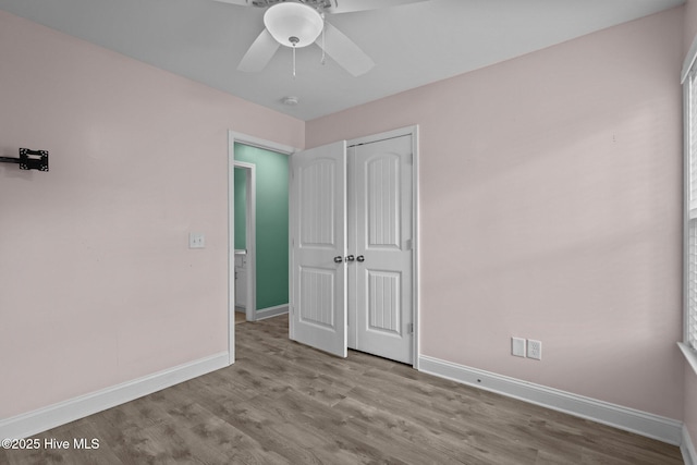 unfurnished bedroom with baseboards, wood finished floors, a closet, and ceiling fan