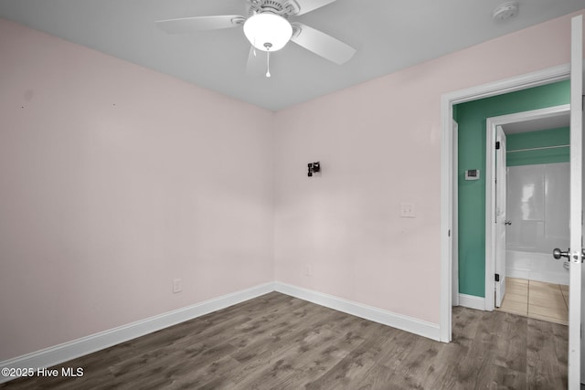 unfurnished room featuring a smoke detector, wood finished floors, baseboards, and a ceiling fan