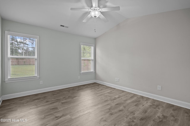 empty room with plenty of natural light, baseboards, wood finished floors, and lofted ceiling