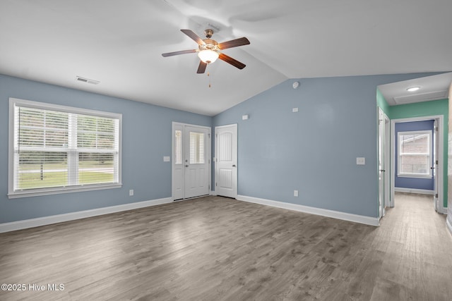 unfurnished living room with a ceiling fan, lofted ceiling, plenty of natural light, wood finished floors, and baseboards