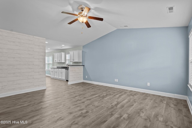 unfurnished living room featuring ceiling fan, wood finished floors, vaulted ceiling, baseboards, and recessed lighting