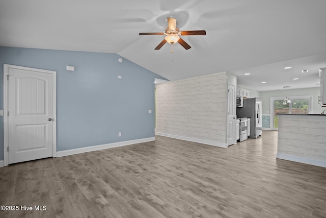 unfurnished living room with a ceiling fan, wood finished floors, baseboards, recessed lighting, and vaulted ceiling