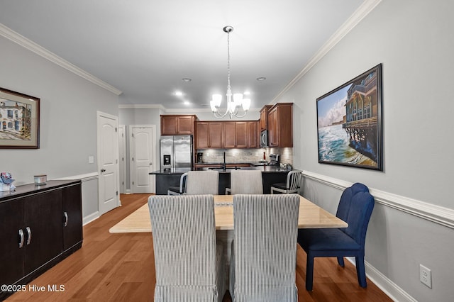 dining area featuring a chandelier, crown molding, and light wood-style flooring