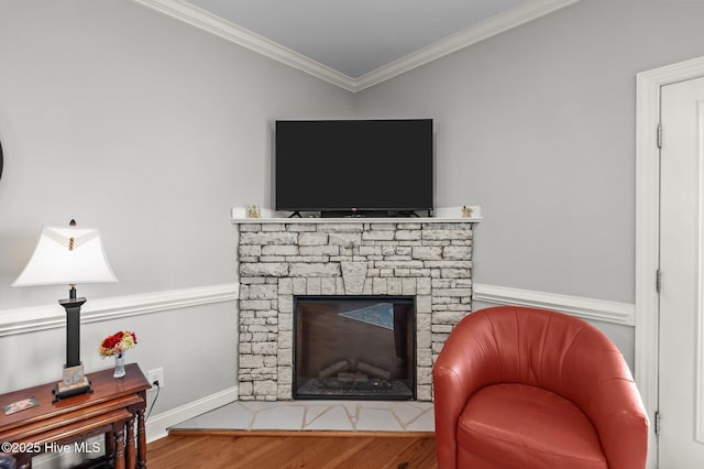 living room with wood finished floors, ornamental molding, a fireplace, and baseboards