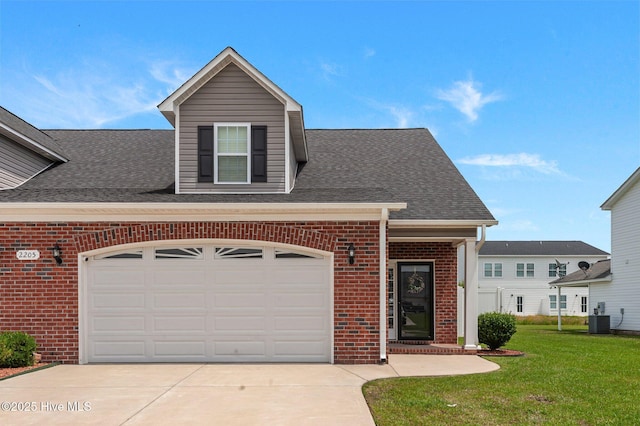 traditional home featuring brick siding, concrete driveway, a front lawn, central AC, and roof with shingles