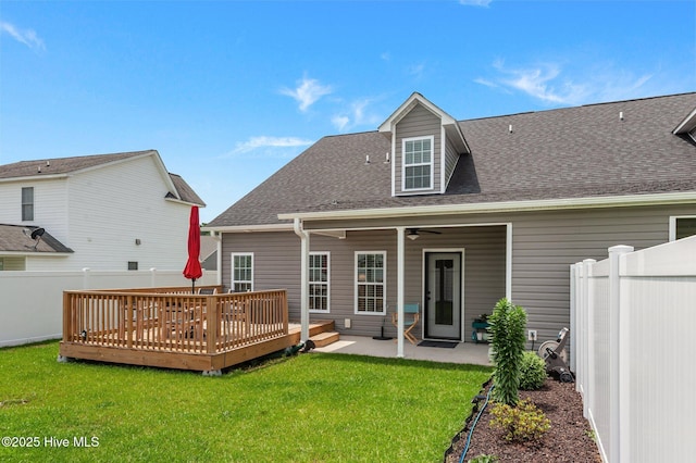 rear view of property with a ceiling fan, a deck, a patio area, and roof with shingles