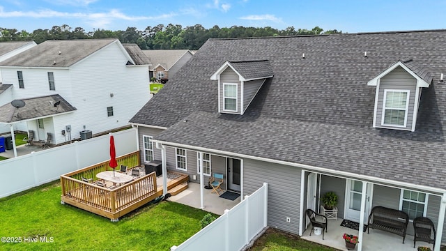 rear view of house with a shingled roof, a wooden deck, central AC, and a patio