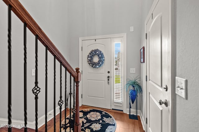 entryway with wood finished floors, stairs, and baseboards