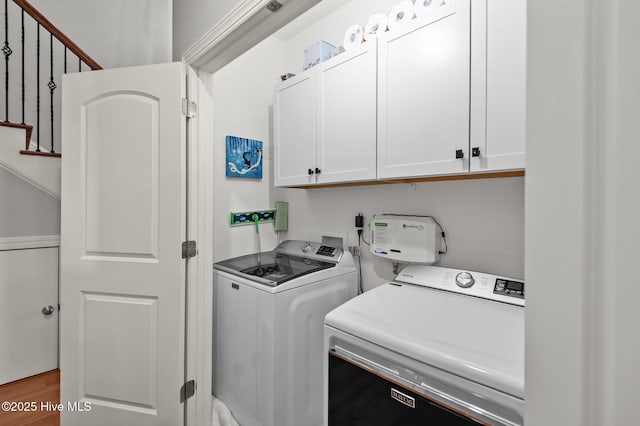 laundry room featuring cabinet space, washer and dryer, and wood finished floors