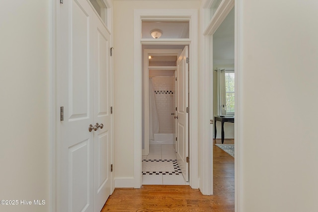 hallway featuring light wood finished floors and ornamental molding