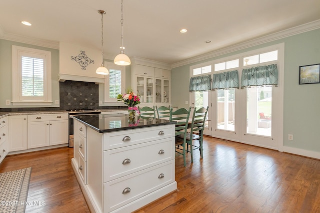 kitchen featuring stainless steel gas range oven, crown molding, white cabinetry, a center island, and decorative backsplash
