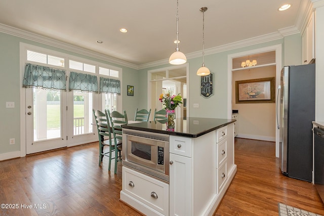 kitchen with appliances with stainless steel finishes, ornamental molding, dark countertops, white cabinetry, and baseboards