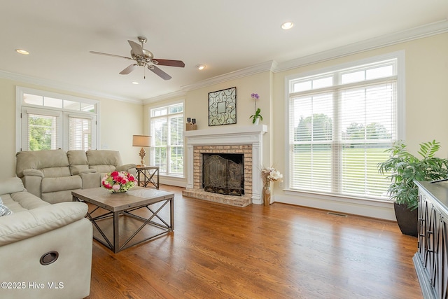 living room featuring a fireplace, ornamental molding, ceiling fan, wood finished floors, and baseboards
