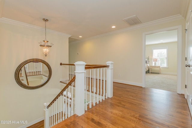 corridor with an upstairs landing, wood finished floors, a chandelier, baseboards, and crown molding