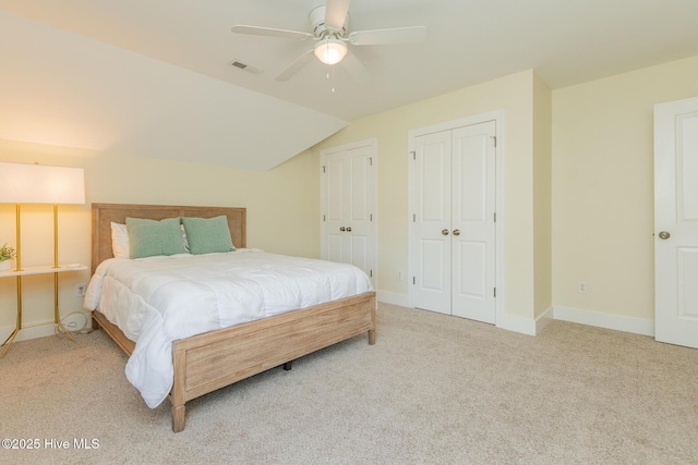 carpeted bedroom featuring lofted ceiling, multiple closets, baseboards, and a ceiling fan