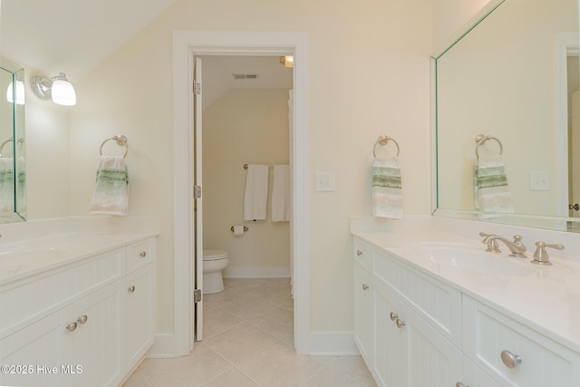 full bath featuring tile patterned flooring, two vanities, baseboards, vaulted ceiling, and toilet