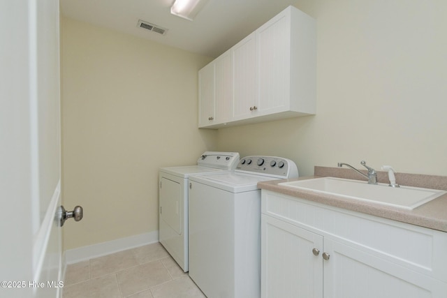 laundry room featuring independent washer and dryer, cabinet space, light tile patterned flooring, and baseboards