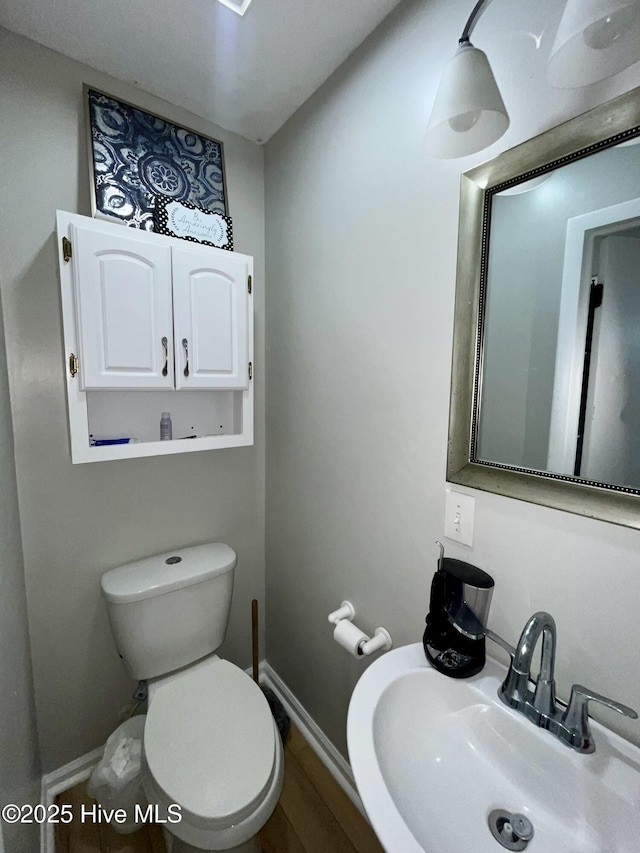 half bathroom featuring a sink, toilet, and baseboards
