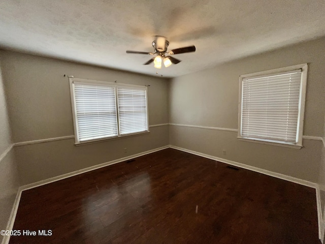 empty room with ceiling fan, dark wood-style floors, and baseboards