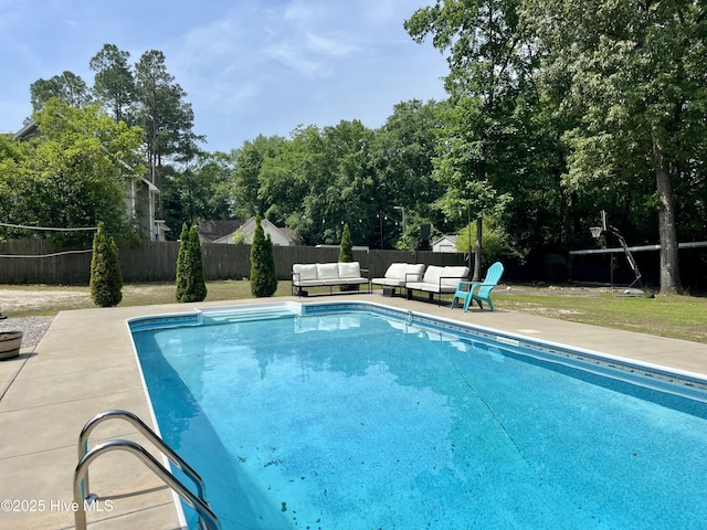 view of swimming pool featuring an outdoor living space, a fenced backyard, a patio area, and view of wooded area