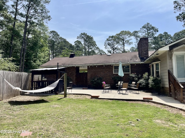 back of property featuring a patio area, a chimney, and brick siding