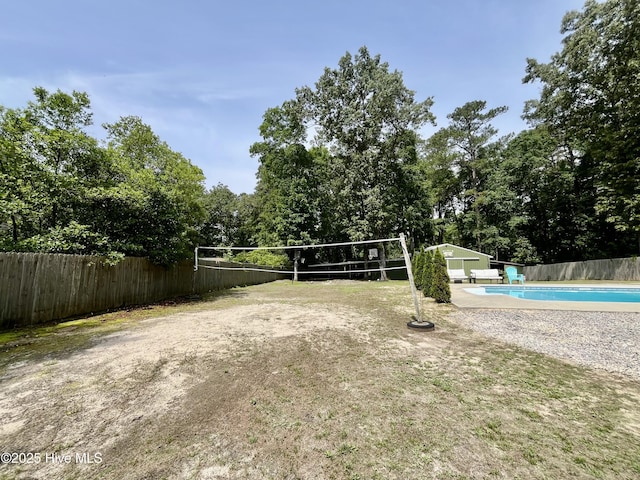 view of community with fence, a pool, volleyball court, an outbuilding, and view of scattered trees