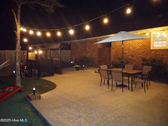 patio at twilight featuring fence and outdoor dining space