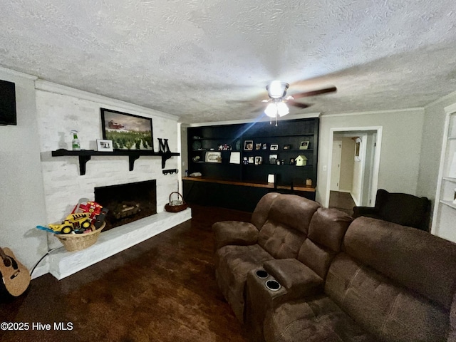 living room featuring a textured ceiling, ceiling fan, built in features, and a large fireplace