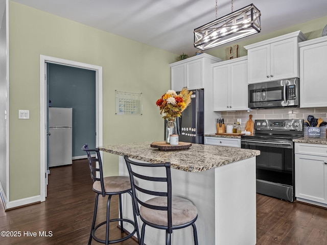 kitchen with stainless steel appliances, dark wood-style floors, a kitchen island, and white cabinets