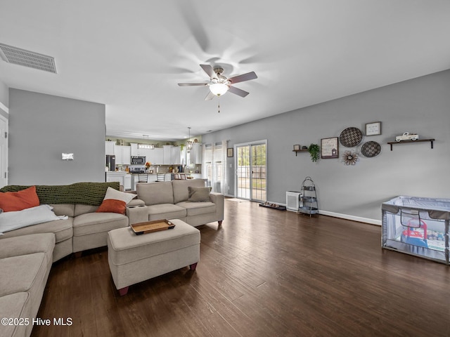 living area with a ceiling fan, dark wood-style flooring, and baseboards