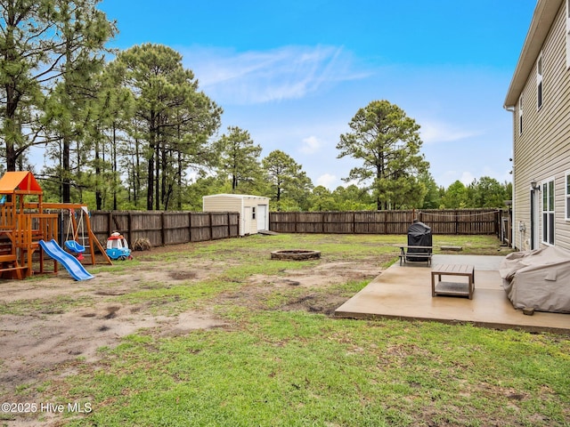 view of yard with an outdoor fire pit, a storage shed, a playground, a patio area, and an outbuilding
