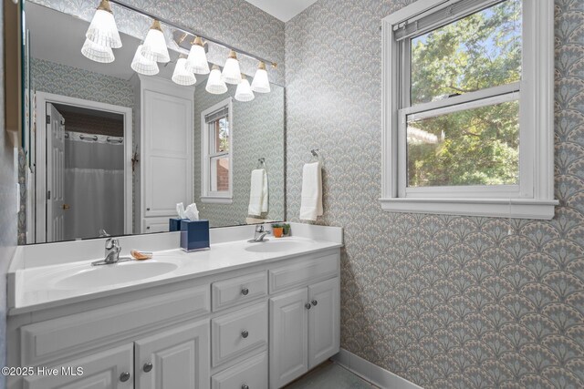 full bathroom featuring wallpapered walls, plenty of natural light, and double vanity