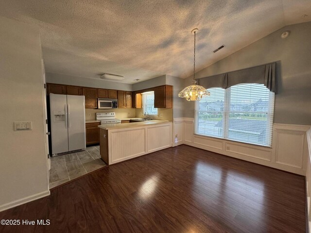 126 W Victoria Ct Unit D, Greenville, NC 27834 - kitchen featuring white appliances, a textured ceiling, dark wood-style flooring, light countertops, and a peninsula