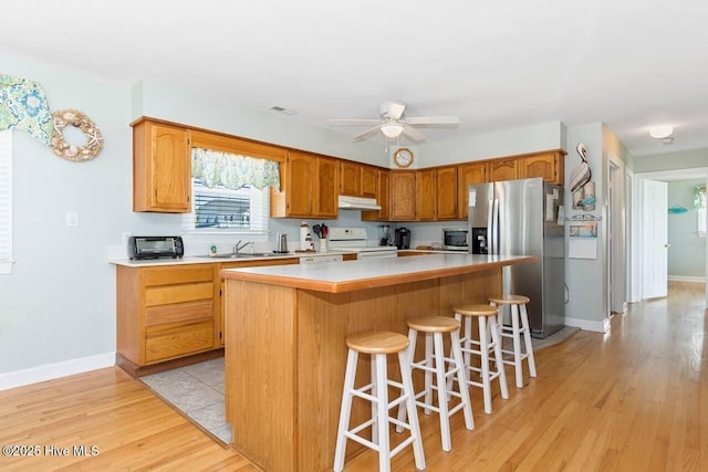 6301 Ocean Dr, Emerald Isle, NC 28594 - kitchen with appliances with stainless steel finishes, under cabinet range hood, light wood-style floors, a kitchen island, and light countertops