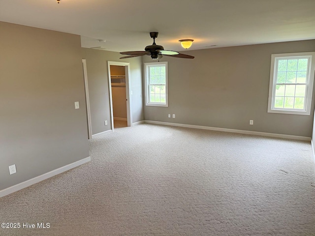 carpeted empty room with baseboards and a ceiling fan