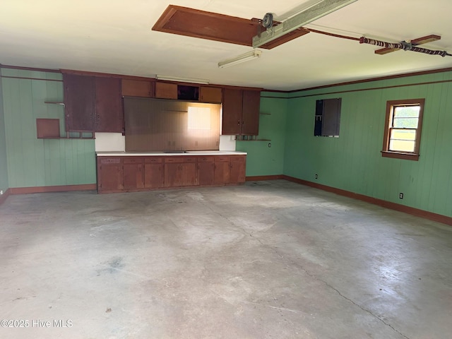 garage with baseboards, electric panel, and wooden walls