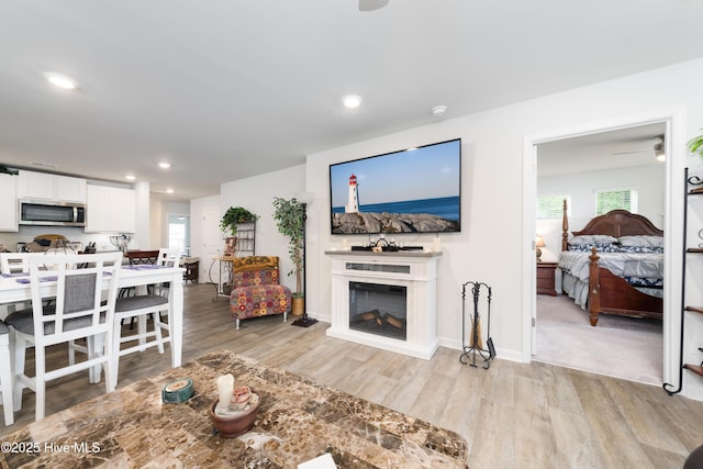 living area with light wood-style flooring, plenty of natural light, recessed lighting, a fireplace, and baseboards