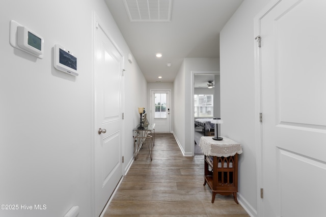 corridor featuring light wood-type flooring, baseboards, and recessed lighting