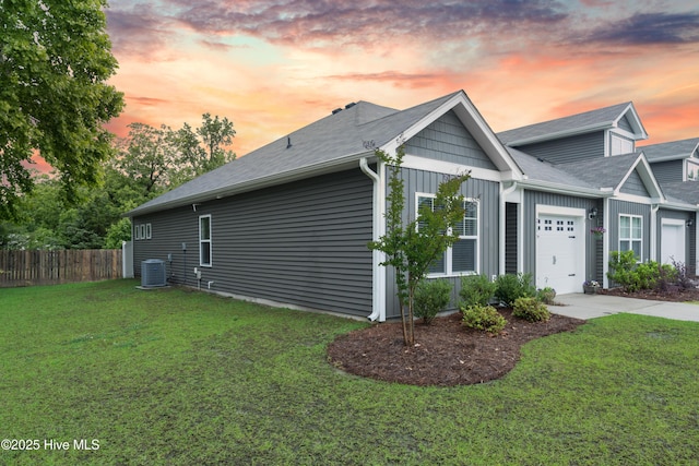 property exterior at dusk featuring an attached garage, central air condition unit, board and batten siding, concrete driveway, and roof with shingles