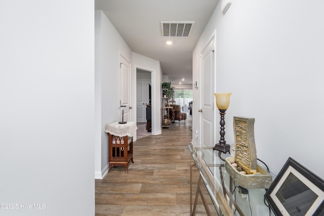 corridor featuring wood finished floors, recessed lighting, and baseboards