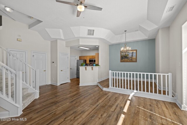 unfurnished living room featuring a ceiling fan, wood finished floors, baseboards, a chandelier, and stairway