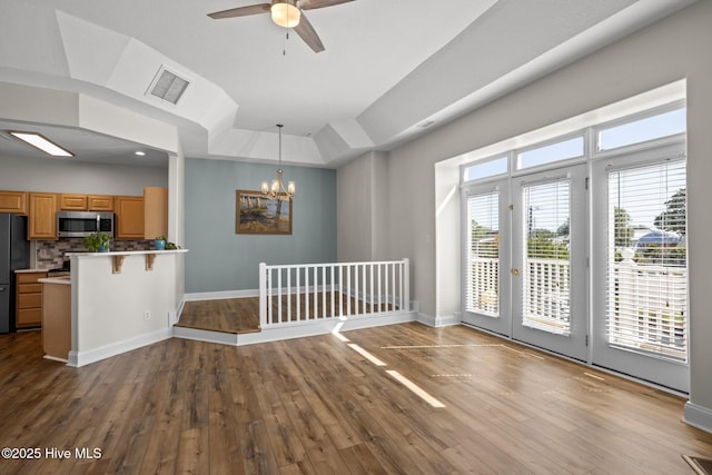 interior space featuring stainless steel microwave, freestanding refrigerator, a peninsula, dark wood-style floors, and a ceiling fan